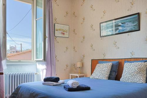 a bedroom with a bed with blue sheets and a window at Villa Rosella in Les Sables-d'Olonne