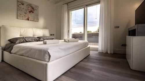 a bedroom with a large white bed and a large window at Villa Sirmione Front Lake in Sirmione