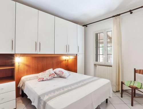 a bedroom with a bed with white cabinets and a chair at Appartamento Tramonto in Capoliveri