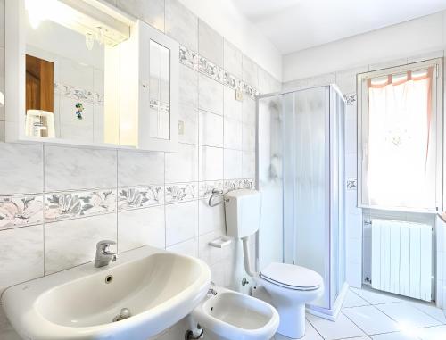a white bathroom with a sink and a toilet at Appartamento Tramonto in Capoliveri