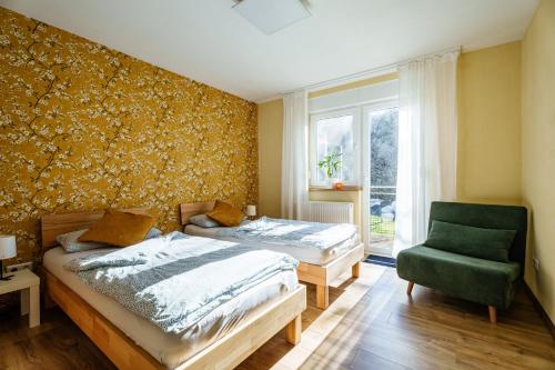 a bedroom with two beds and a green chair at s'Lähmes auf der Schwend in Kappelrodeck