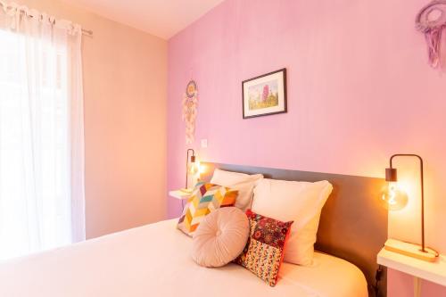a bedroom with pink walls and a bed with pillows at Chambre - Orchis in Aroue