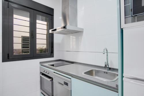 a white kitchen with a sink and a window at Apartamentos Bellamar in Barbate