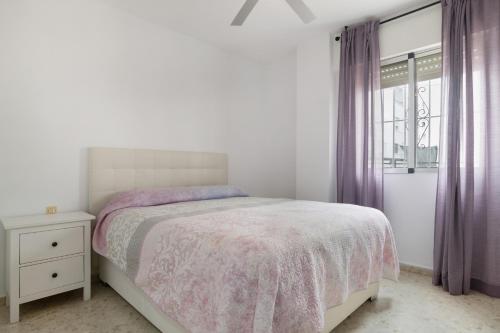 a white bedroom with a bed and a window at Casa En El Centro De Barbate in Barbate