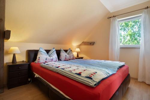 ein Schlafzimmer mit einem Bett mit einer roten Decke und einem Fenster in der Unterkunft Julenhof in Loitz