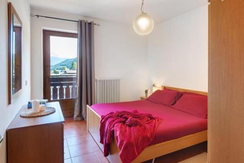 a bedroom with a red bed and a window at Cima de' Piazzi Apartment 1 in Valdidentro