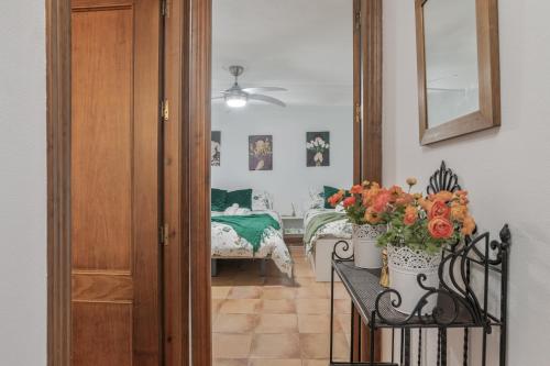 a hallway with a table with flowers and a bedroom at Mi Ilusión in Grazalema