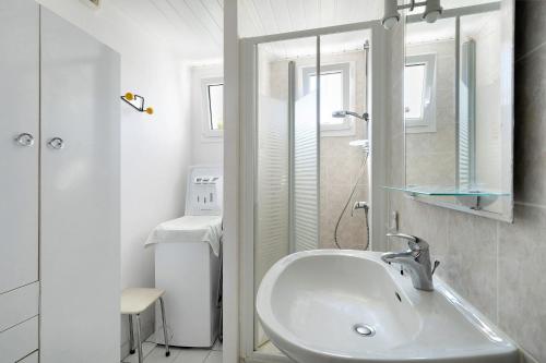 a white bathroom with a sink and a mirror at Maison Pêcheur, jardin et plage -1 in Pornic