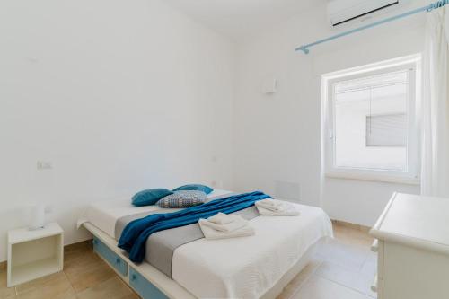 a white bedroom with two beds and a window at Casa Anastasia in Otranto