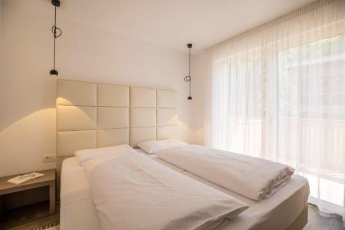 a white bed in a room with a window at Apartment Cinch Residence Bun Ste in San Vigilio Di Marebbe