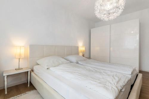a white bedroom with a large bed and a chandelier at Haus 15 in Offenburg
