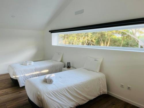 two beds in a room with a large window at Forest Village in Azenhas do Mar