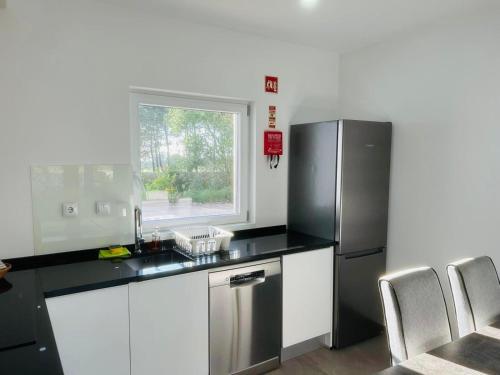 a kitchen with a stainless steel refrigerator and white cabinets at Forest Village in Azenhas do Mar