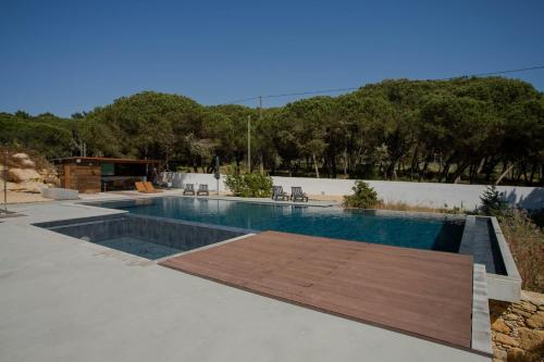a swimming pool with a wooden deck in a yard at Forest Village in Azenhas do Mar