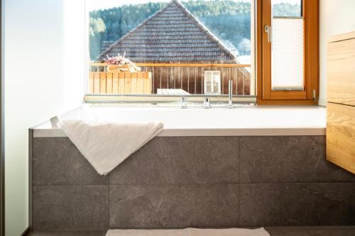 a bathroom with a bath tub in front of a window at Ferienhaus Kornspeicher in Hornberg