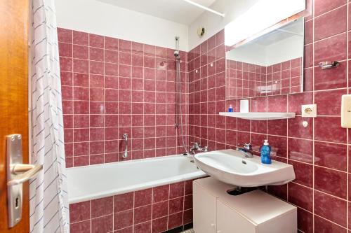 a red tiled bathroom with a sink and a tub at Über den Wolken in Höchenschwand