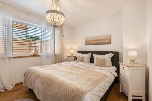 a white bedroom with a large bed and a chandelier at bei Thérèse - Erdgeschoss in Miltach
