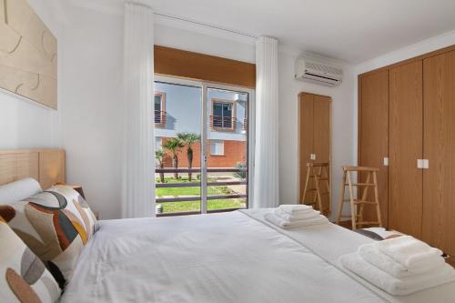 a bedroom with a bed and a large window at Almadrava House in Tavira
