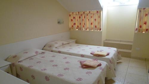 two beds in a small room with pink sheets at Playa de las Americas Cool Duplex in Playa de las Americas