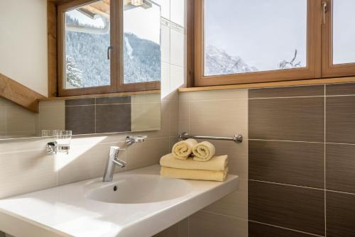a bathroom with a sink and a window and towels at Runcac Apt Gomina in San Vigilio Di Marebbe