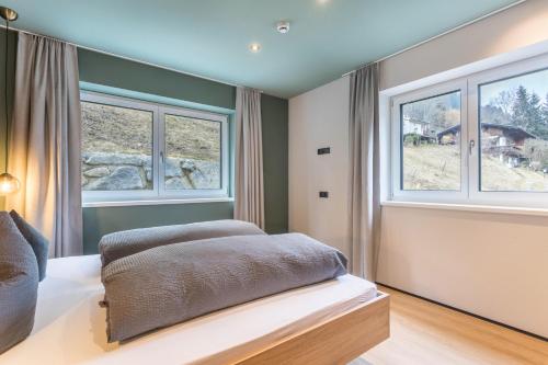 a bedroom with a bed with two windows at Luisalle Top 3 in Auffach