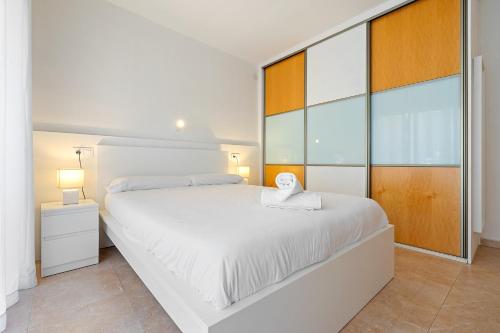 a white bedroom with a large bed and large windows at Center Beach Calafell in Calafell