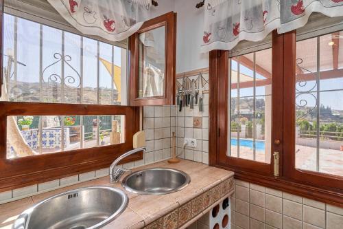 a kitchen with two sinks and windows with a view at Casa Torre del Manzano in Torrox
