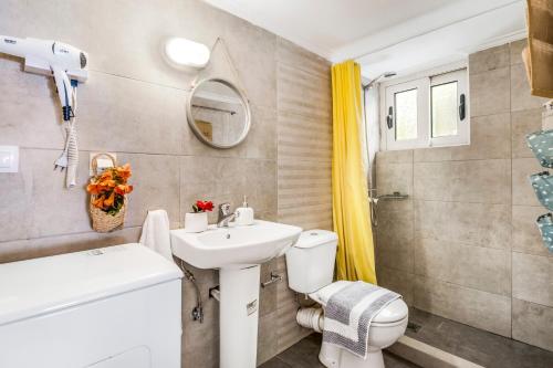 a bathroom with a sink toilet and a mirror at Oceanida Aelia room in Nikiana