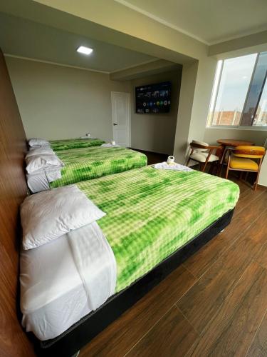 two beds with green and white sheets in a room at Hotel Atenas in Barranca