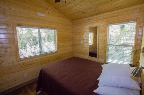 a bedroom with a bed in a wooden cabin at Lake of the Springs Camping Resort Cottage 1 in Oregon House