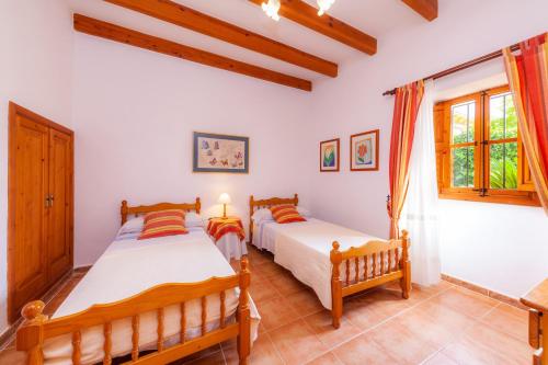 two beds in a room with white walls and windows at S'alqueria Vell in Campanet