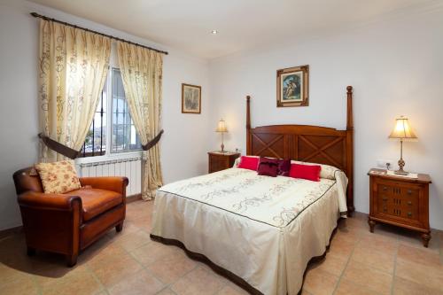 a bedroom with a bed and a chair and a window at Casa La Mirada in Cómpeta