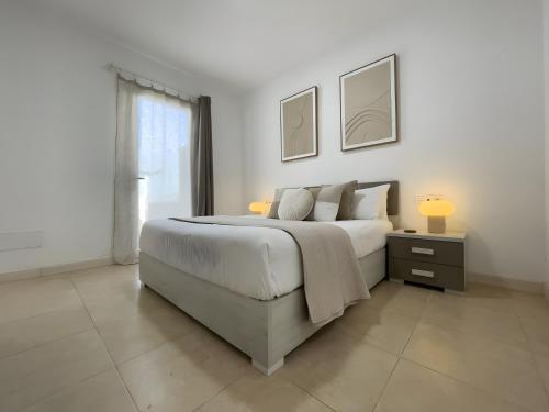 a white bedroom with a large bed and a window at Villa Lychee in Playa Blanca