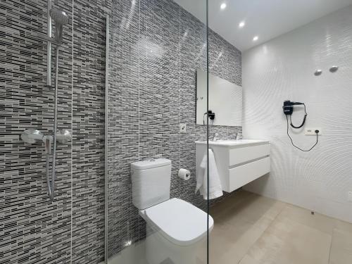 a bathroom with a toilet and a shower and a sink at Villa Lychee in Playa Blanca