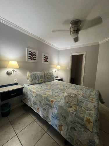 a bedroom with a bed and two tables and a fan at Ocean & Pool View - Top Floor - 2 Pools - Hot Tub - GYM - Tennis ct - SS03 in Galveston