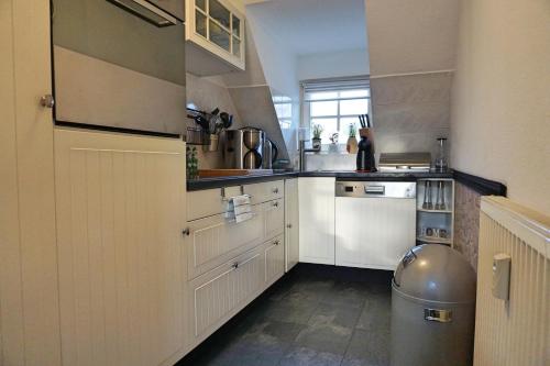 eine Küche mit weißen Schränken und einem Mülleimer in der Unterkunft Zuhause in der Ferne in Sassnitz