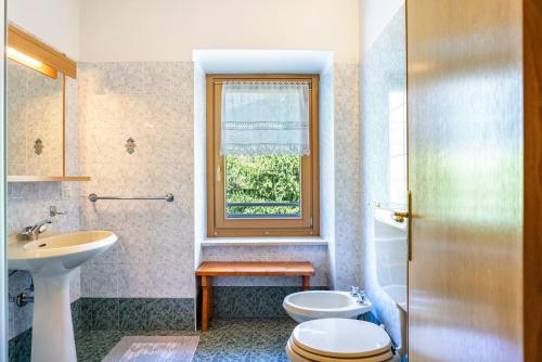 a bathroom with a sink and a toilet and a window at Casa Ai Laresi 1 in Peio