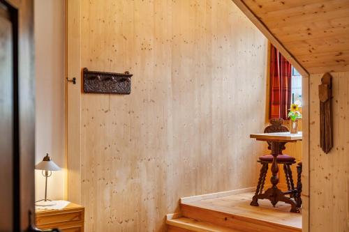 a room with a wooden wall with a table and a stool at Ferienunterkünfe Beim Posthalter in Oberammergau