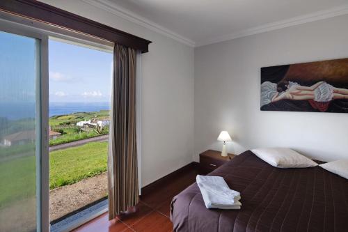a bedroom with a bed and a large window at Vivenda do Monte in Achadinha