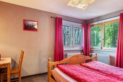 a bedroom with a bed and windows with red curtains at Blackforest Ferienwohnung in Sankt Georgen im Schwarzwald