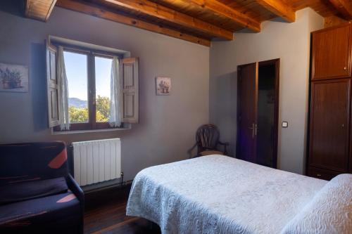 a bedroom with a bed and a chair and a window at Fuenternilla in Carranza