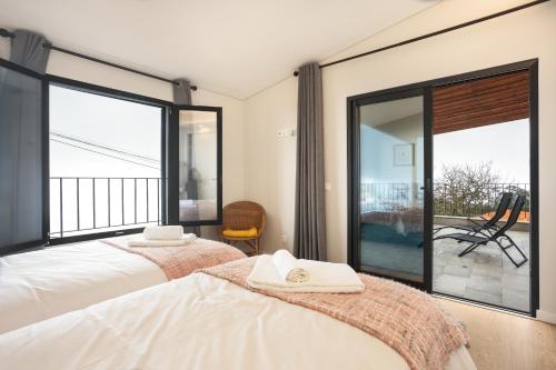 a bedroom with two beds and large windows at Referta Apartamento T1 in Prazeres