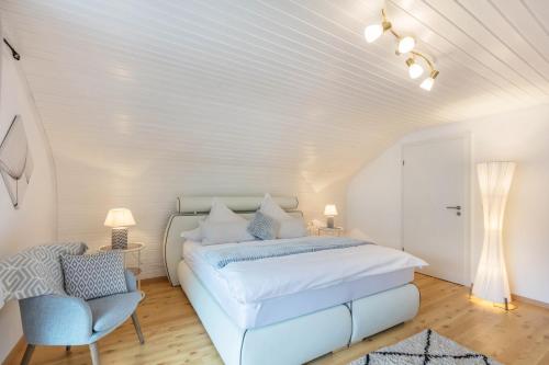 a white bedroom with a bed and a chair at Ferienwohnung Haus Oehlberg in Todtmoos