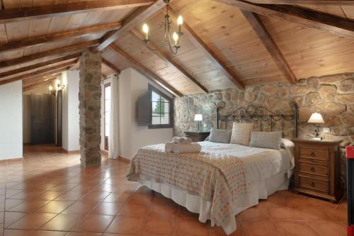 a bedroom with a bed and a stone wall at Villa los mellizos in Arriate