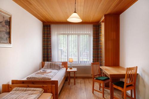 a bedroom with two beds and a table and a window at Ferienunterkünfe Beim Posthalter in Oberammergau