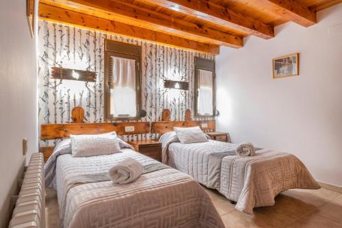 two beds in a room with wooden ceilings at Casa Batlle Ginebro in Les Iglésies