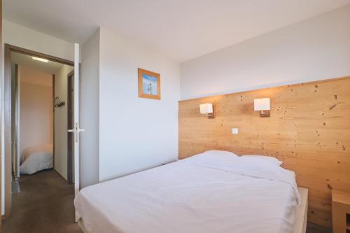 a bedroom with a white bed with a wooden wall at appartement duplex in LʼHuez