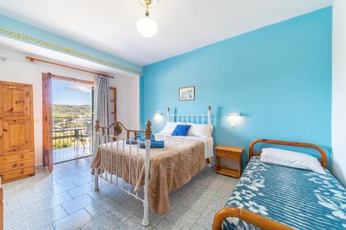a blue bedroom with two beds and a balcony at Captain Spiros Studios in Paleokastritsa