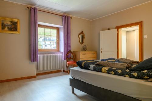a bedroom with a bed and a window with purple curtains at Gîte Le Rempart in Guebwiller