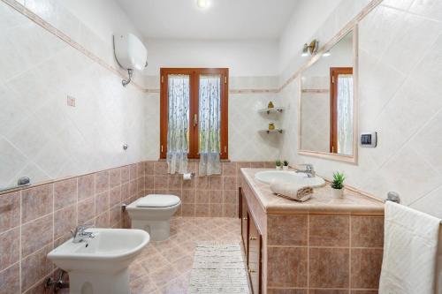 a bathroom with a sink and a toilet and a mirror at Sole Mare di Barbara in Chia